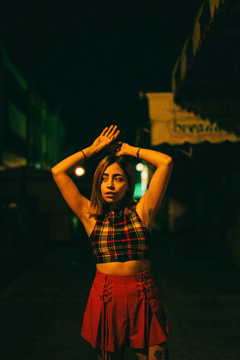 Young woman standing by illuminated street at night