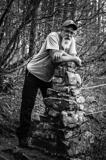 Portrait of senior man leaning on rock at forest