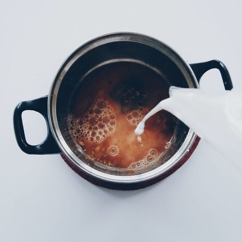 Close-up of pouring milk into tea pot