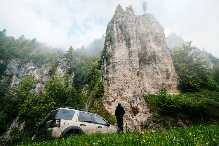Man and car against rock formation in summer