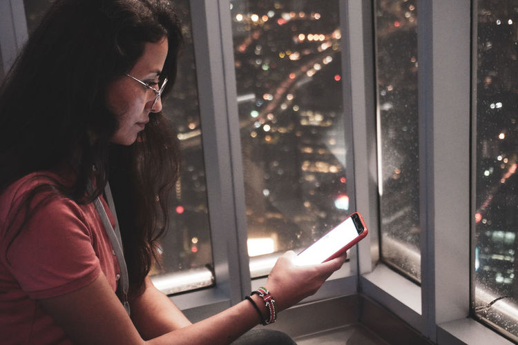 Side view of woman using mobile phone at night