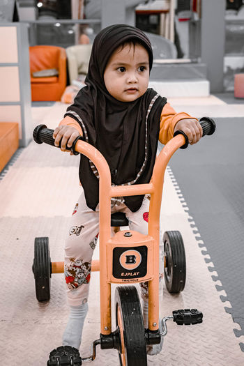 Little baby girl learning to ride a tricycle