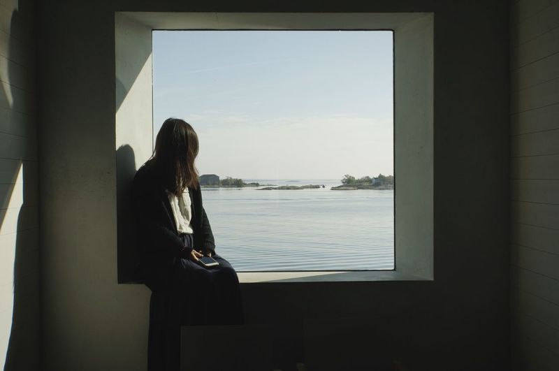 Woman looking at sea through window