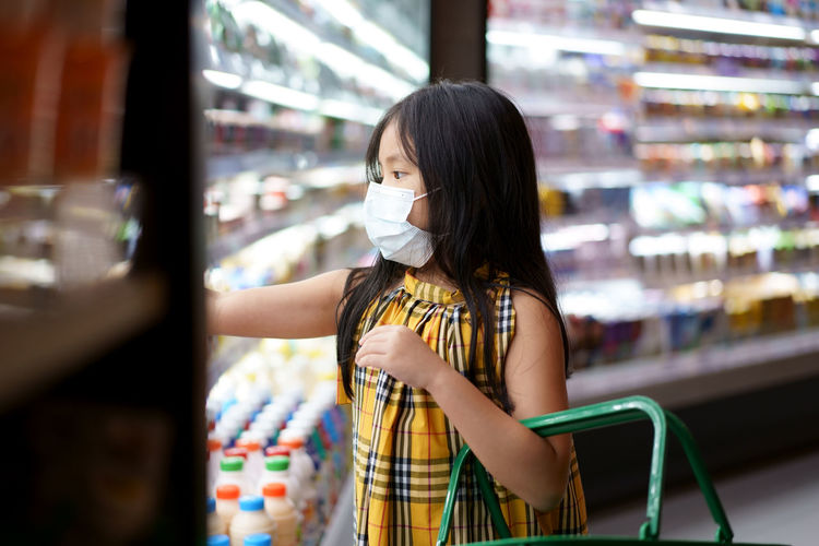 Cute girl wearing mask shopping at supermarket