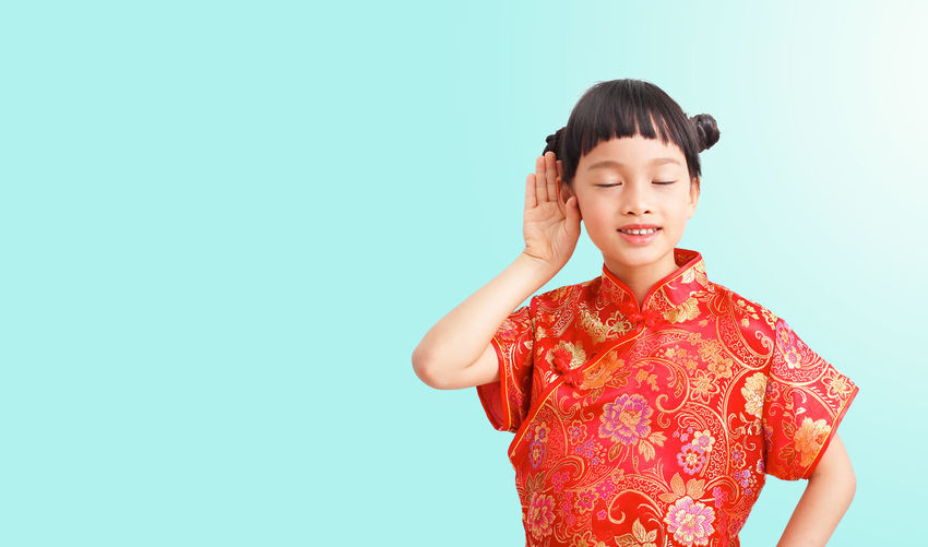 Girl listening while standing against blue background