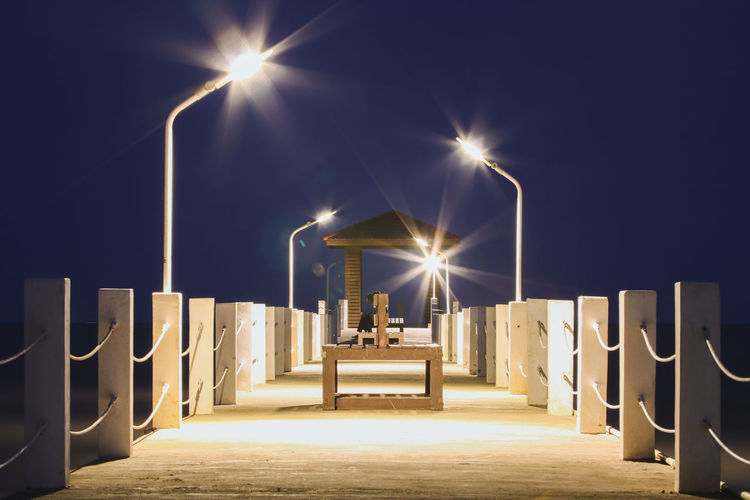 Illuminated street lights against sky at night