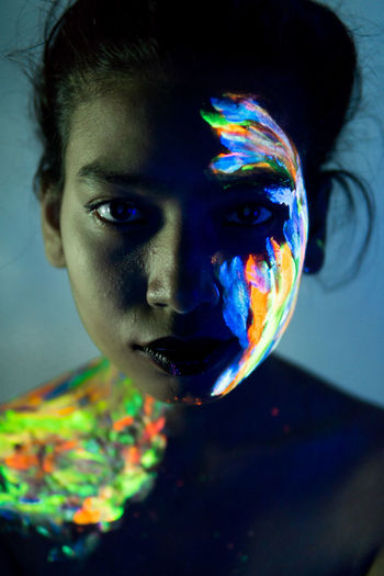 Close-up portrait of young woman with paint on face and shoulder