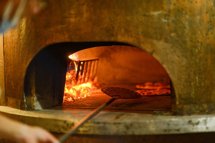 Pizza maker cooking pizzas in wood oven
