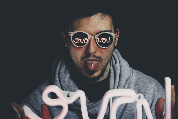 Portrait of man wearing sunglasses against black background