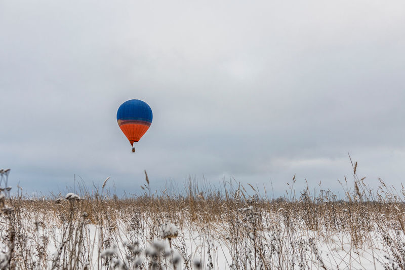 Hot air balloon flying over field against sky