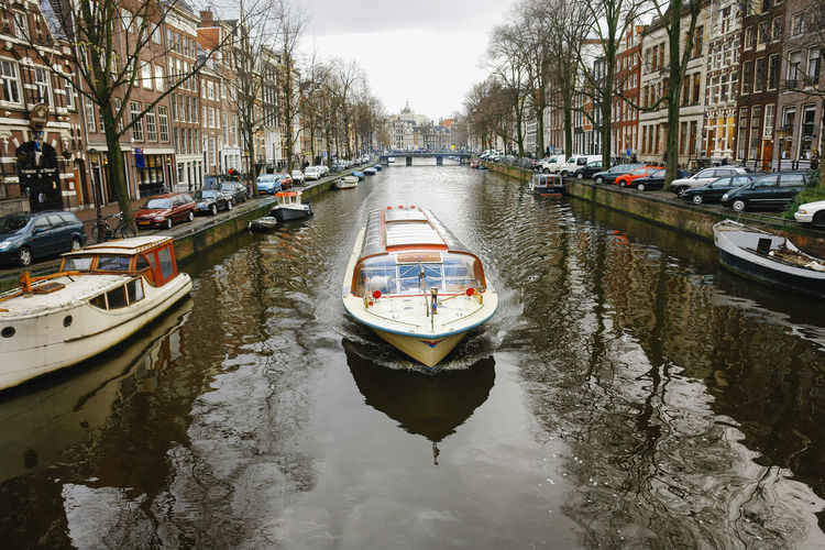 Boats moored in canal amidst city