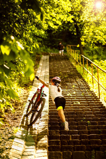 Low angle view of girl with bicycle climbing steps
