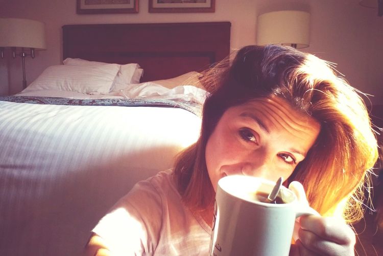 Portrait of woman showing coffee cup at home