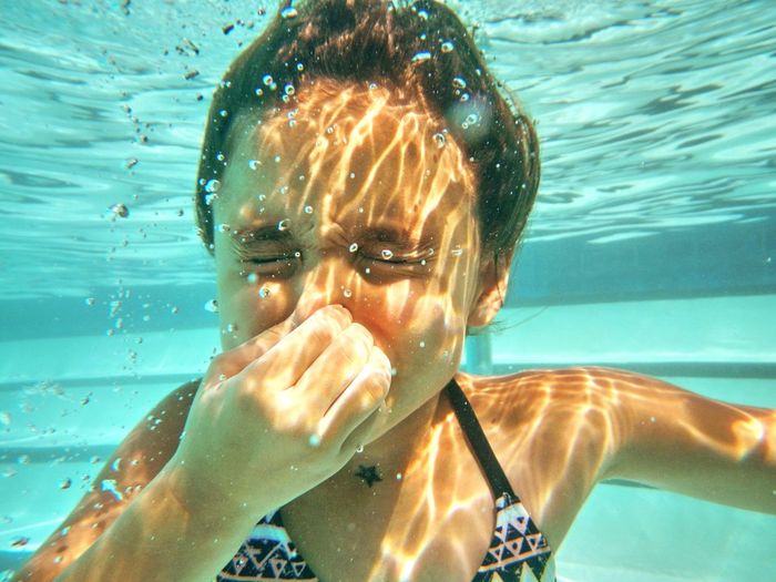 Cute girl holding breath underwater in swimming pool
