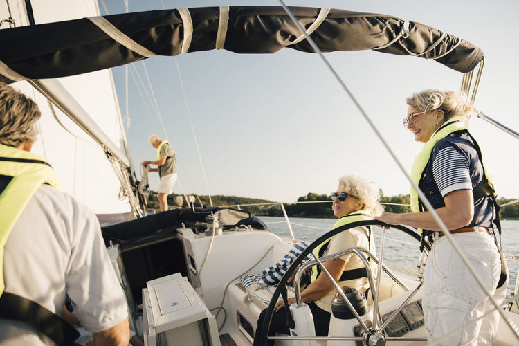 Senior male and female friends spending leisure time in sailboat on sunny day