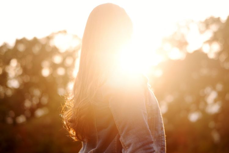 Portrait of woman standing against bright sun