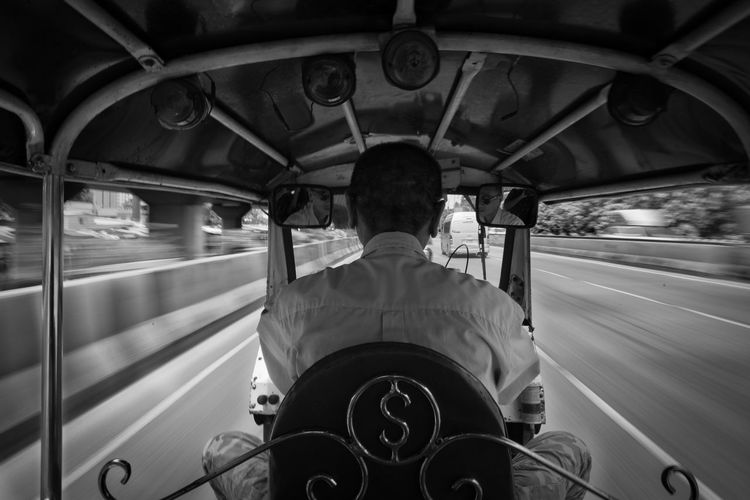 Rear view of man riding jinrikisha in city