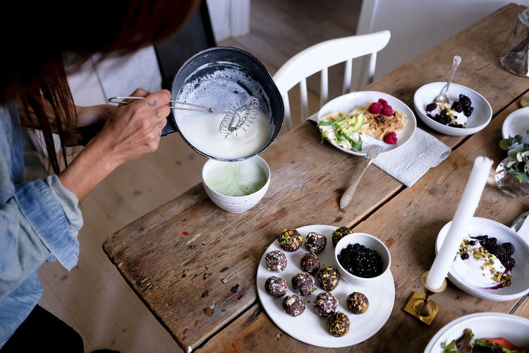 Cropped image of woman preparing matcha tea in bowl at table