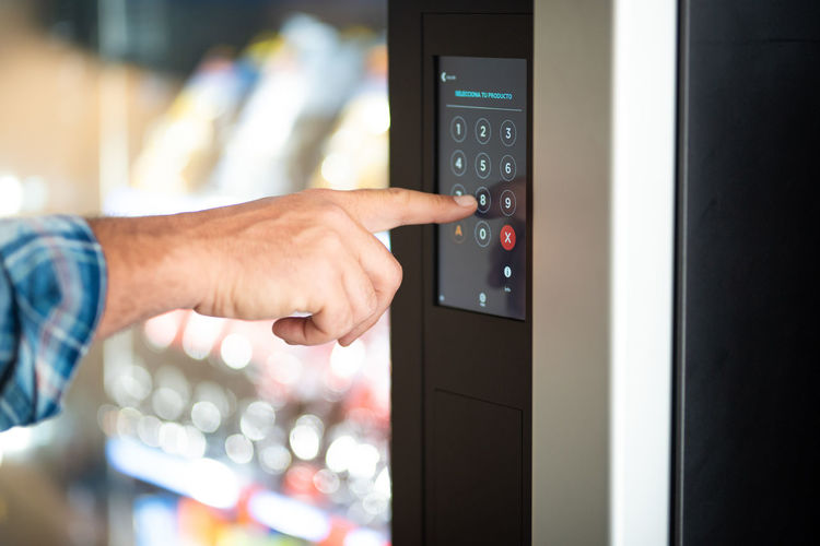 Cropped hand of man touching vending machine