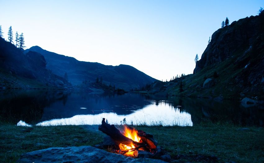 Bonfire on rock by lake against sky