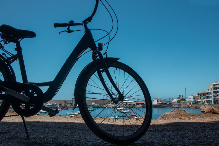 Bicycle by street against clear blue sky
