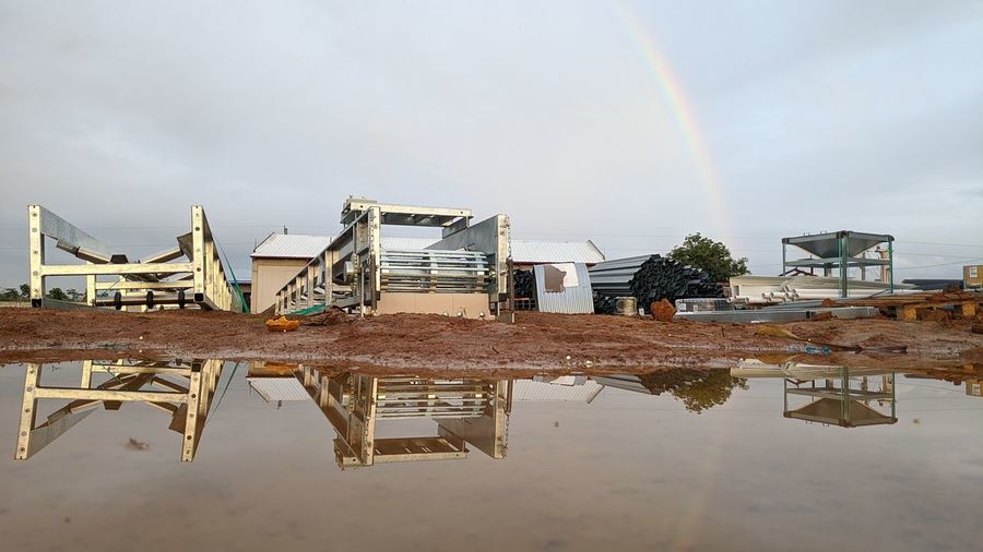 Reflection of abandoned building on puddle against sky