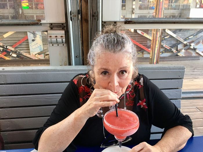 Portrait of mature woman drinking cocktail while sitting at restaurant