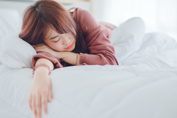 Close-up of woman sleeping on bed at home