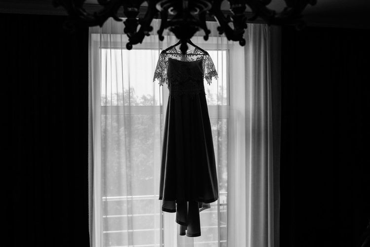 Wedding gown hanging by curtain on wall