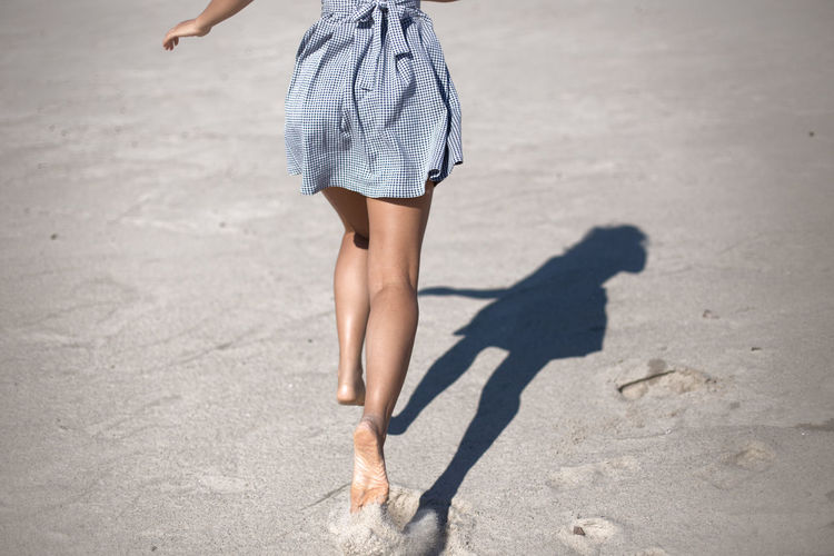 Low section of woman running on sand at beach