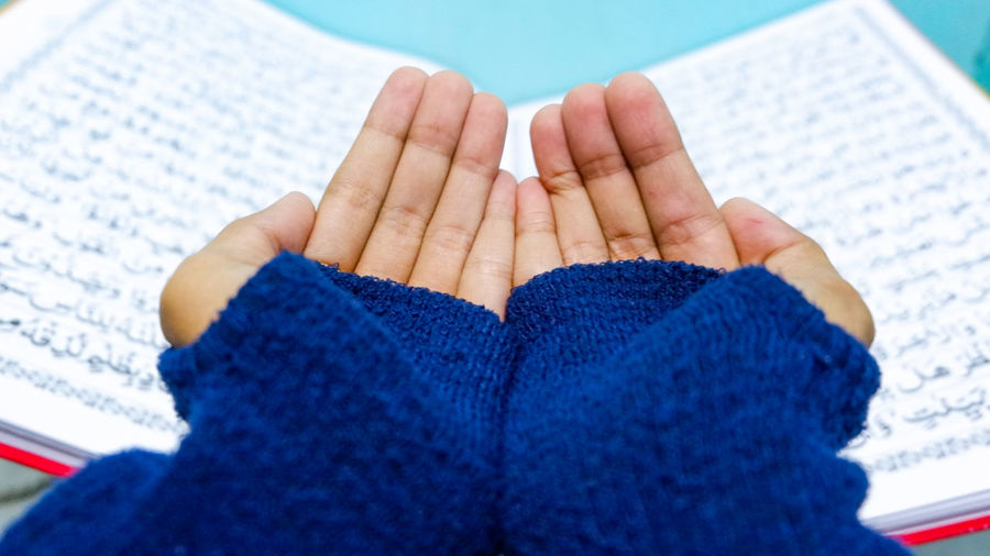 Cropped image of cupped hands against koran