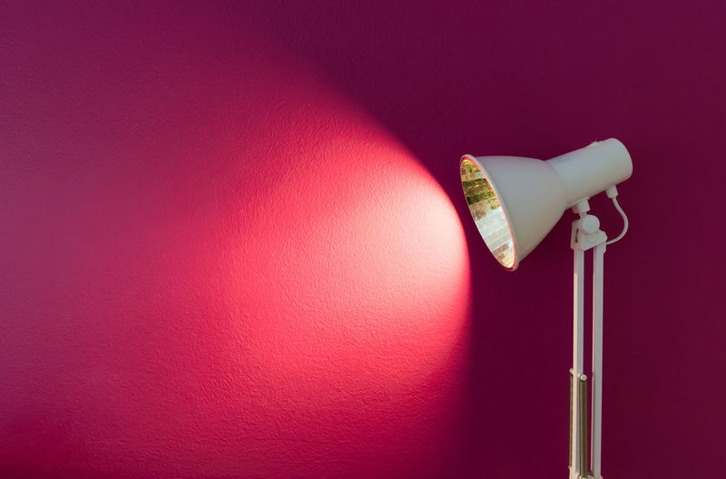 Close-up of electric lamp against pink wall