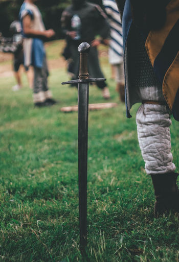 Low section of person with sword standing on field