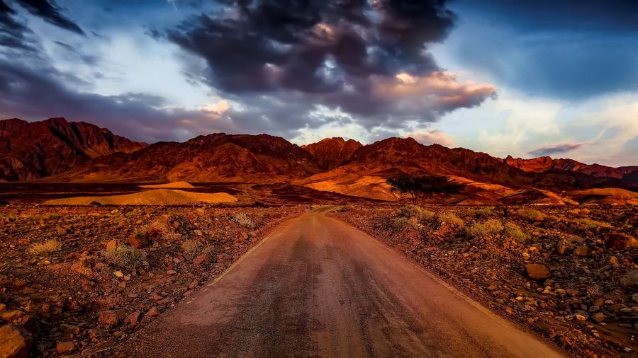 Scenic view of road through desert at sunset