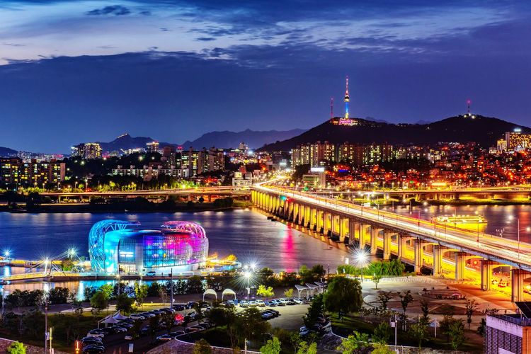 High angle view of illuminated buildings by river against sky