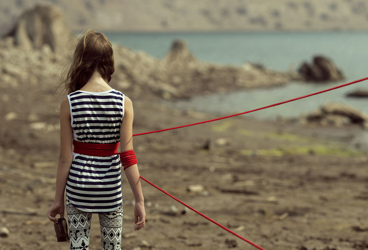 Rear view of teenage girl tied up with red rope