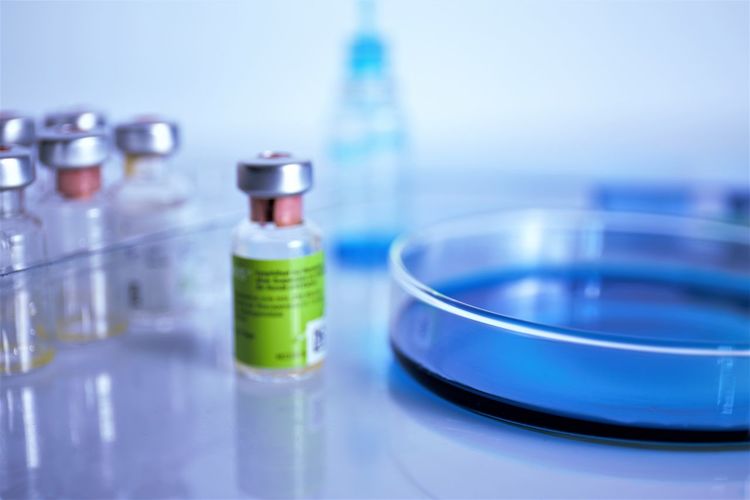 Close-up of vials by petri dish against white background