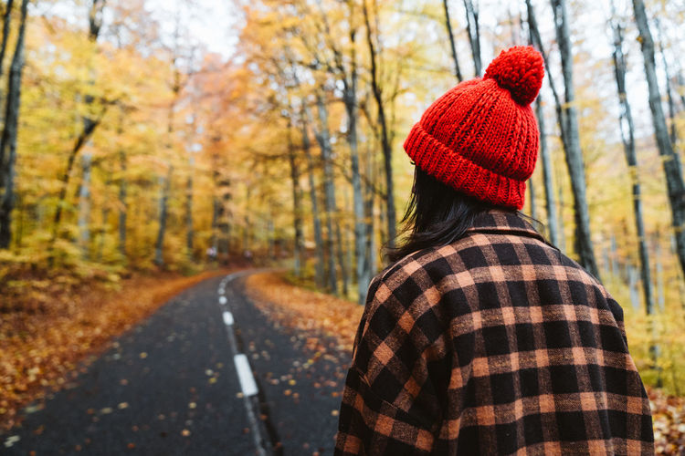 Rear view of person wearing hat in forest during autumn