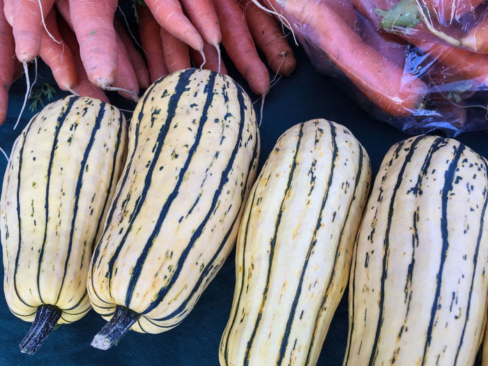 Delicata squash and carrots for sale at market stall
