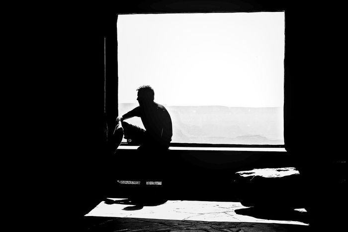 Silhouette man in front of window at home
