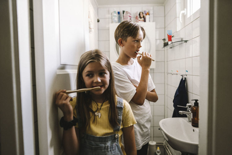 Brother and sister brushing teeth in bathroom