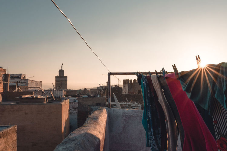 Clothes drying on roof against buildings in city against sky