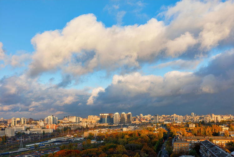 The sun's rays break through gray clouds, exposing the blue of the sky  autumn cityscape of kyiv.