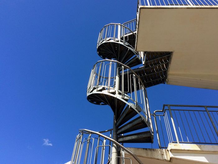 Low angle view of spiral stairs against clear blue sky