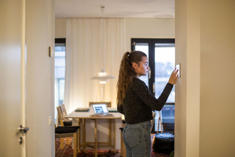 Teenage girl using digital tablet mounted on wall at home