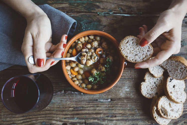 Woman eating mediterranean soup with bread, close-up