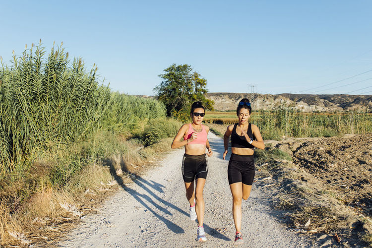 Woman with instructor running on footpath
