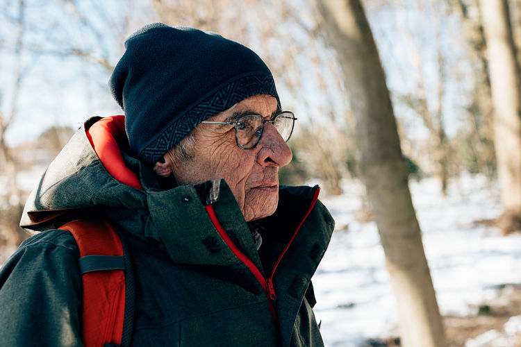 Side portrait of senior healthy active man hiking outdoors in the snow