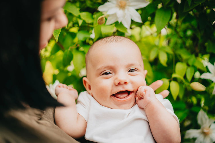Midsection of mother holding cute baby boy against plants
