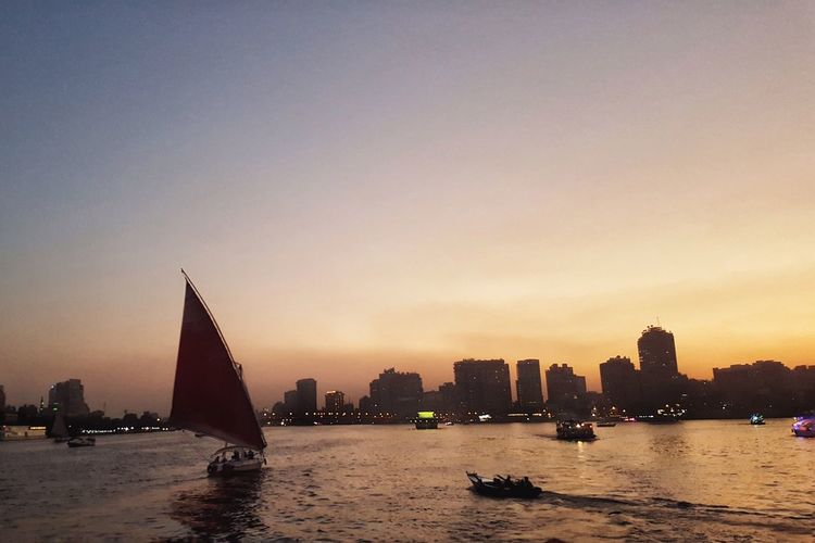 Silhouette boats sailing in sea against sky during sunset